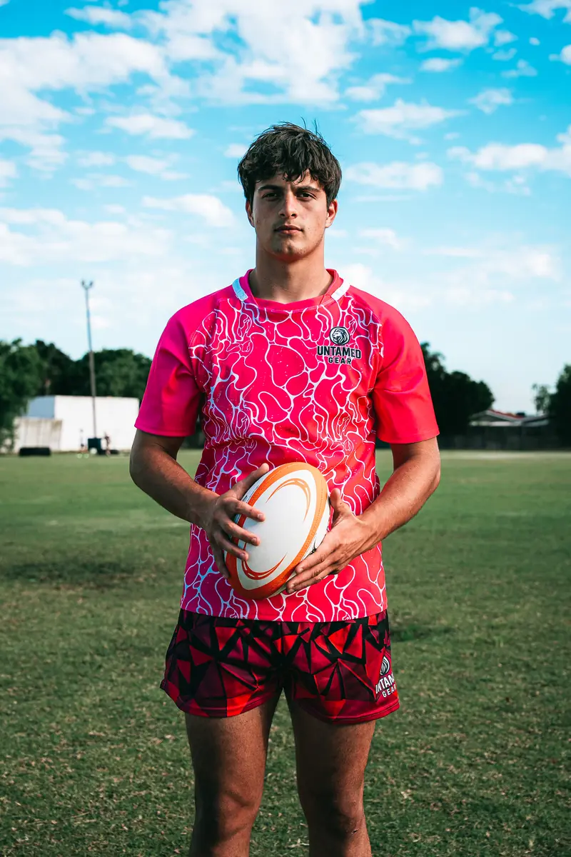 Untamed Gear athlete holding rugby ball in pink rugby jersey